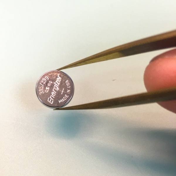 carefully handling the battery by its sides to avoid a short circuit